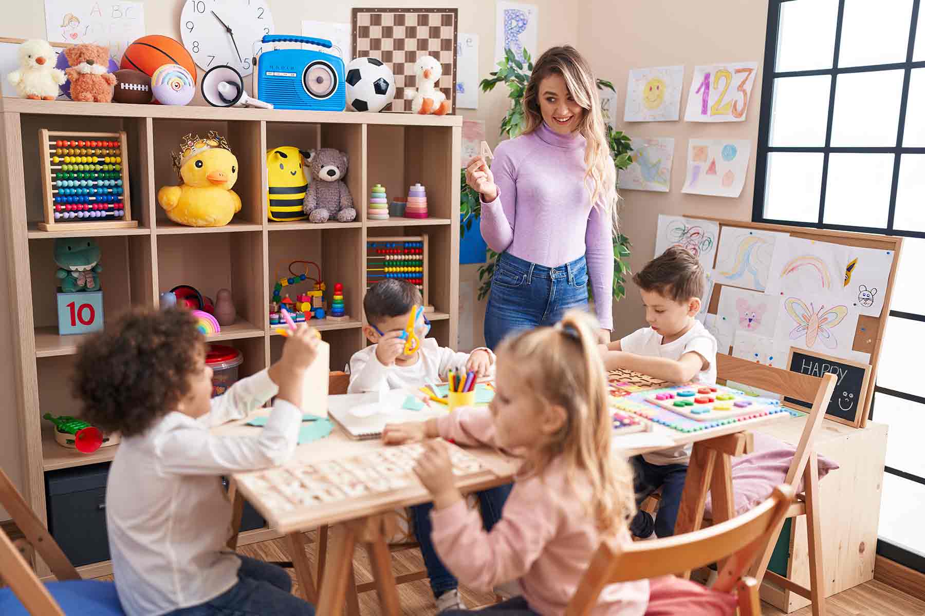 A daycare teacher guiding children during a vocabulary lesson with colorful letters and numbers