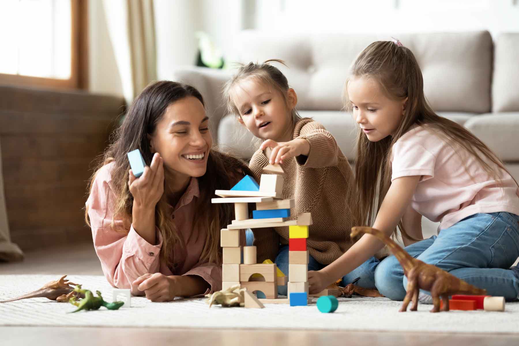 An au pair playing with two young children.