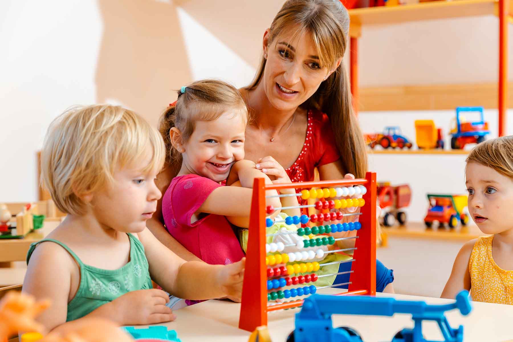 A teacher guides young children through a fun abacus learning activity A teacher guides young children through a fun abacus learning activity