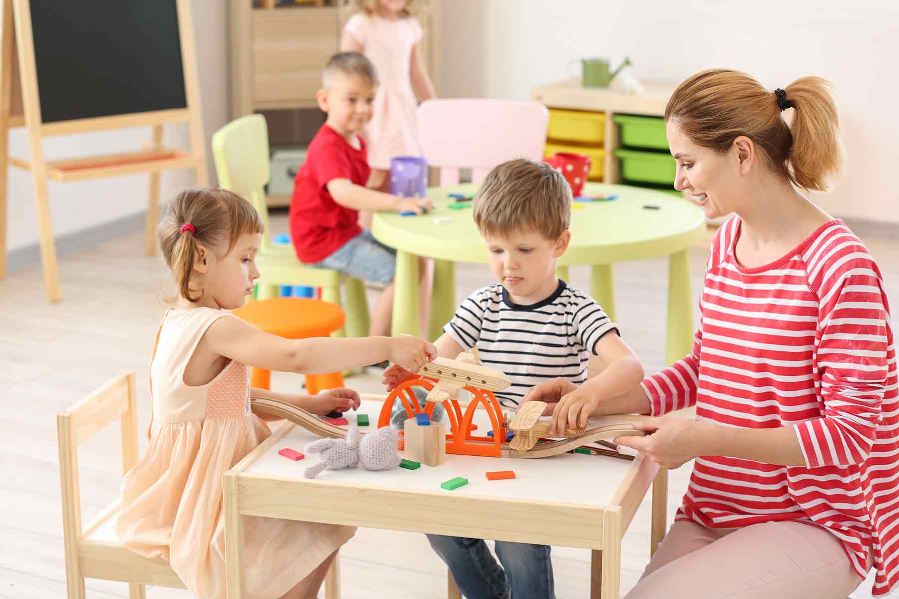 A daycare teacher guiding the young children during their playtime in the classroom