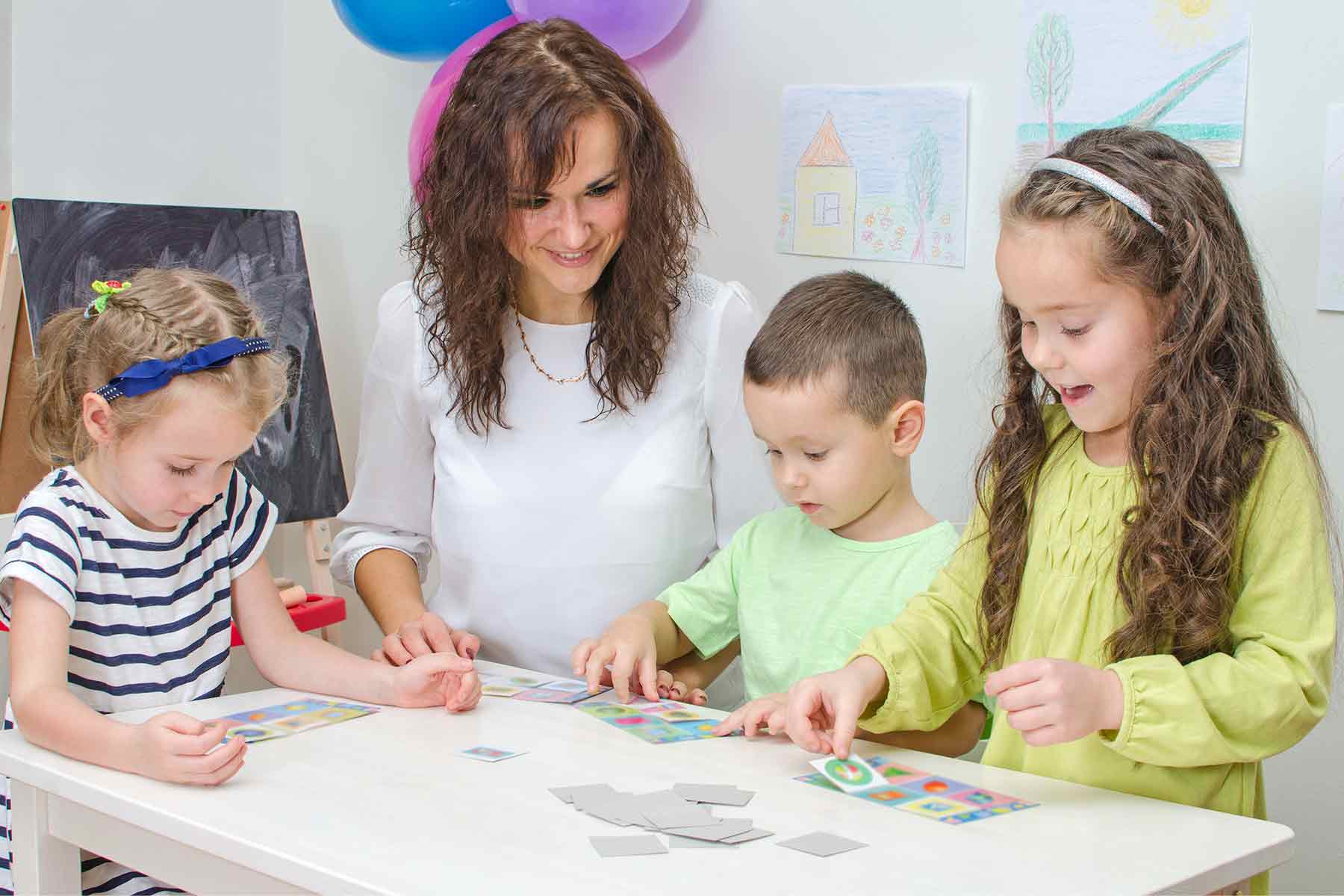 A daycare teacher guiding children as they work on an educational puzzle activity