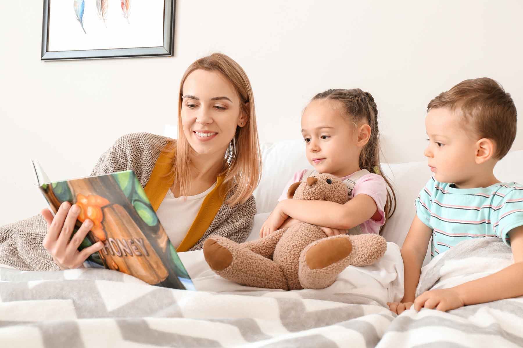 A babysitter or nanny reading a bedtime story to young children.