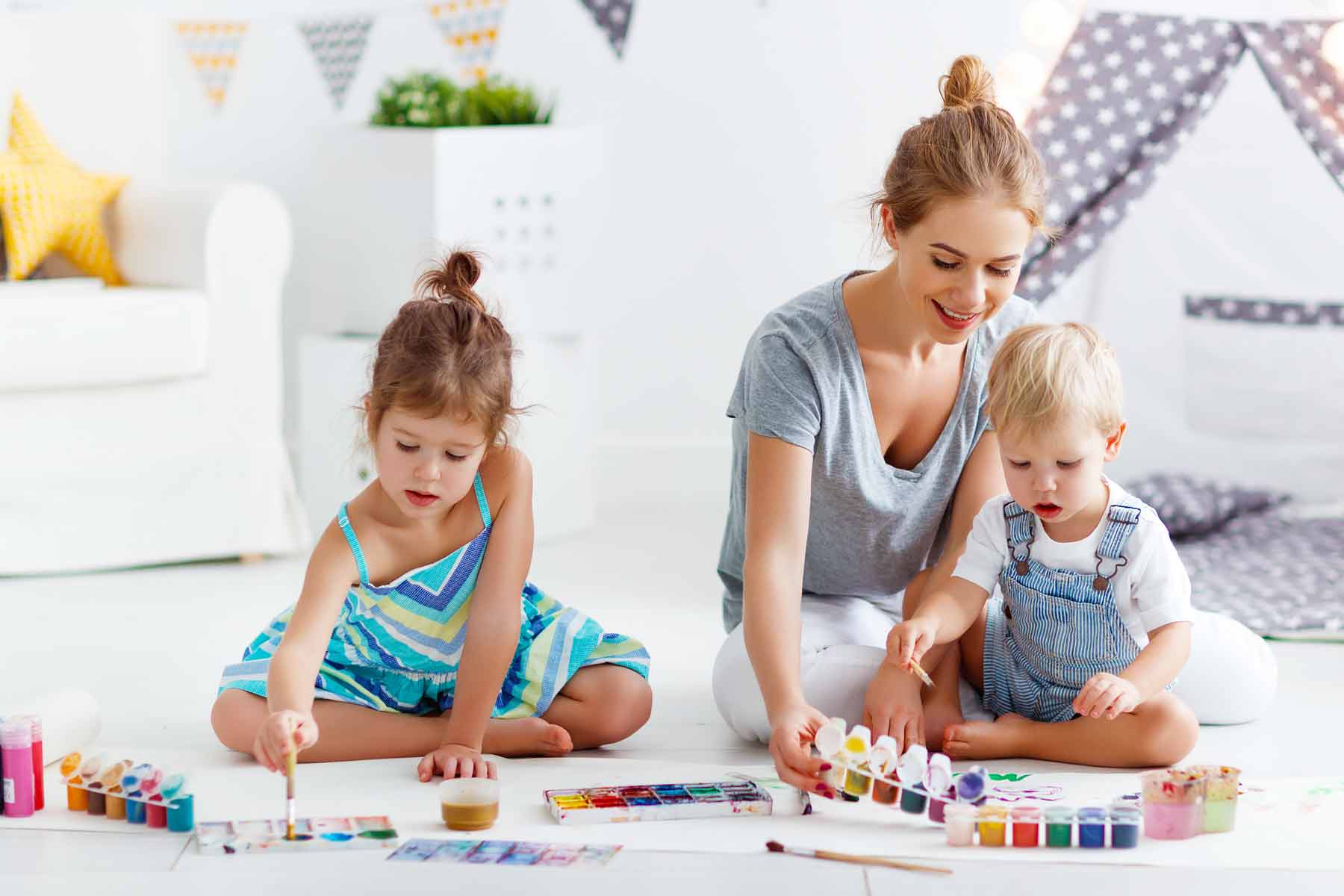 A babysitter working on arts and crafts with two young children.