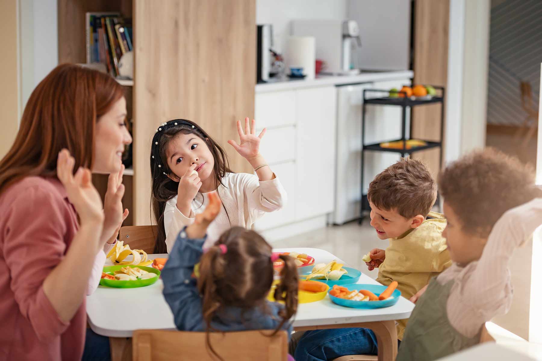 Daycare teacher playing with a diverse group of children at snack time