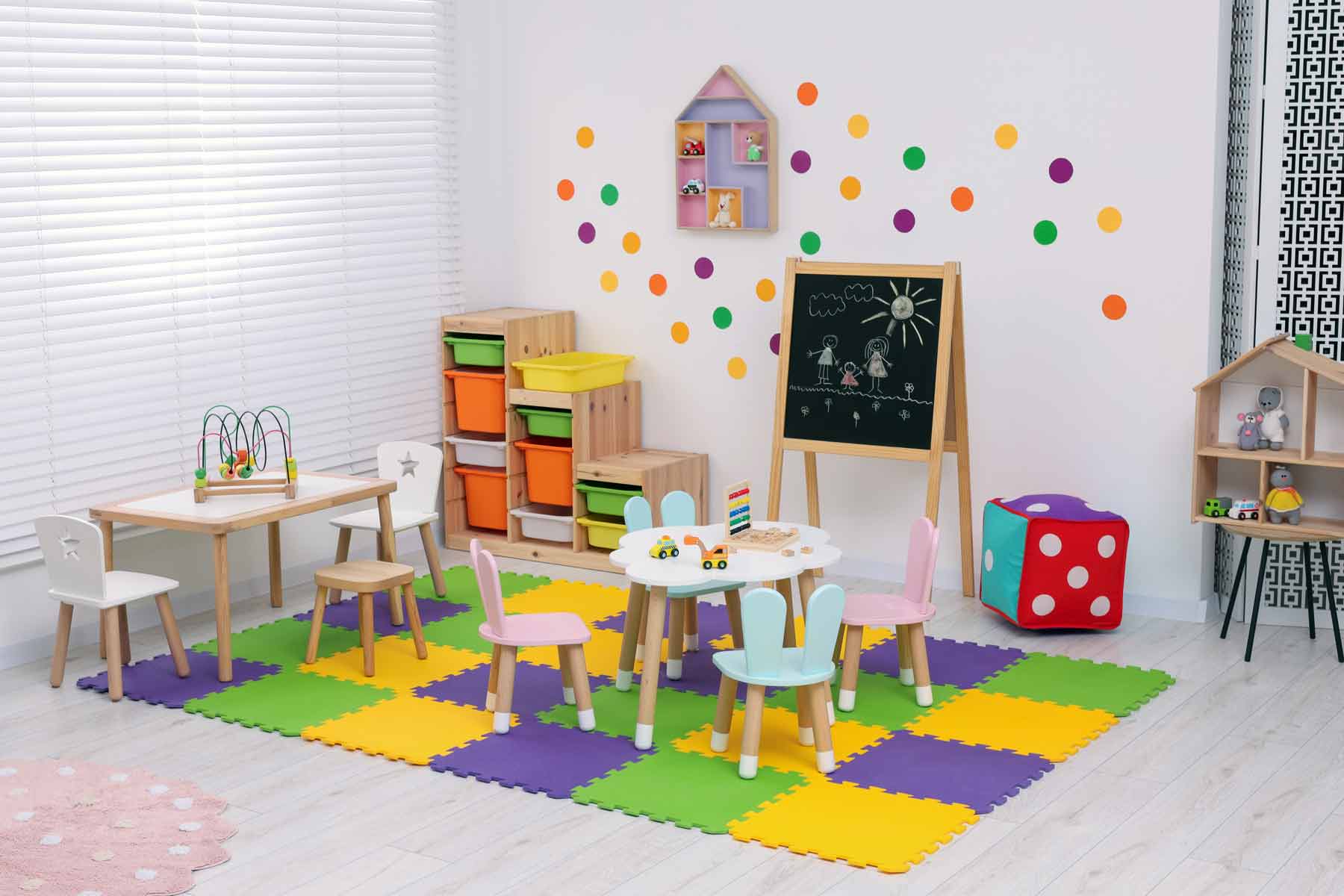 Small child-sized tables and chairs, toys, shelves, and a chalkboard at a daycare center Small child-sized tables and chairs, toys, shelves, and a chalkboard at a daycare center