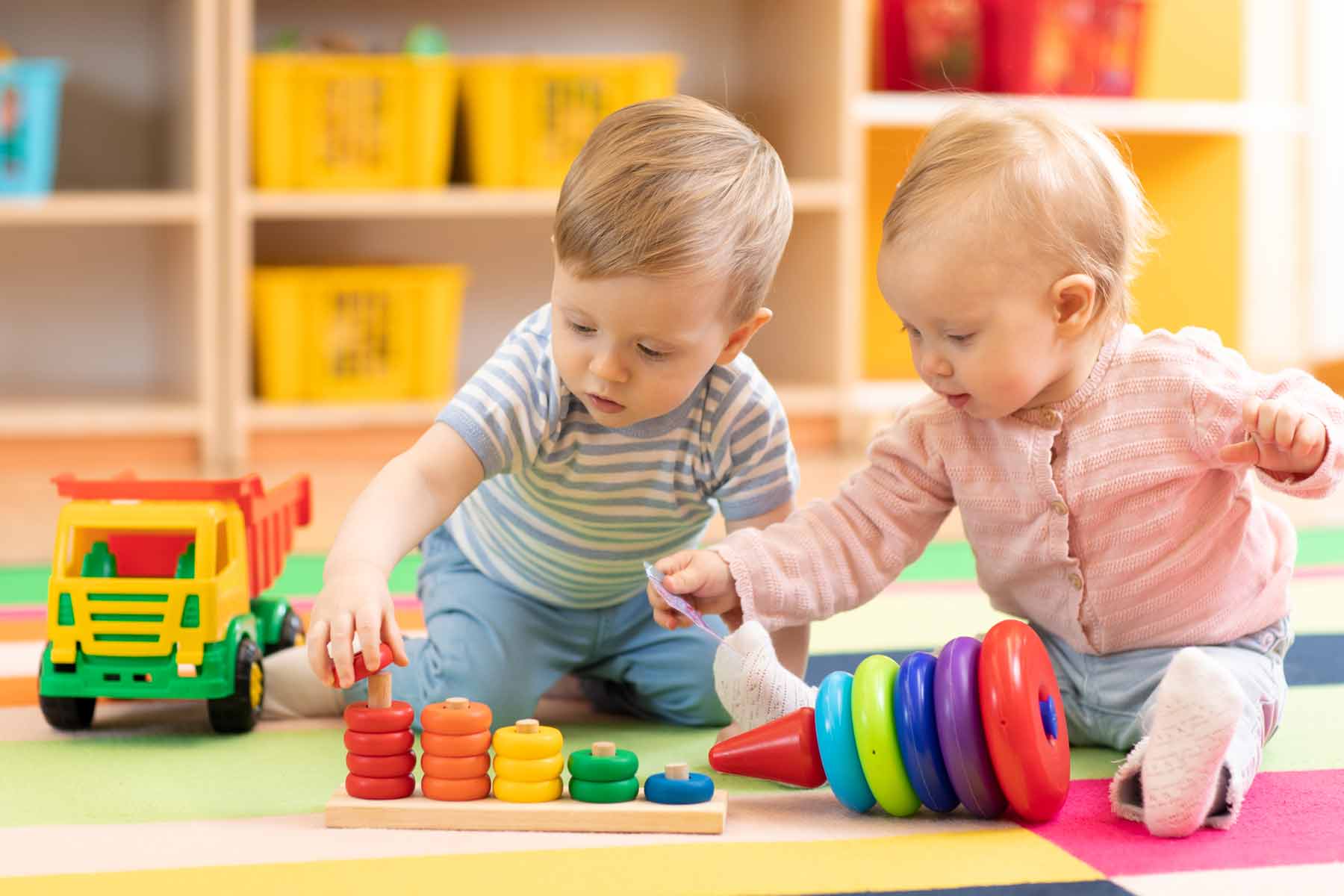 Cute children playing with colorful stacking toys in daycare