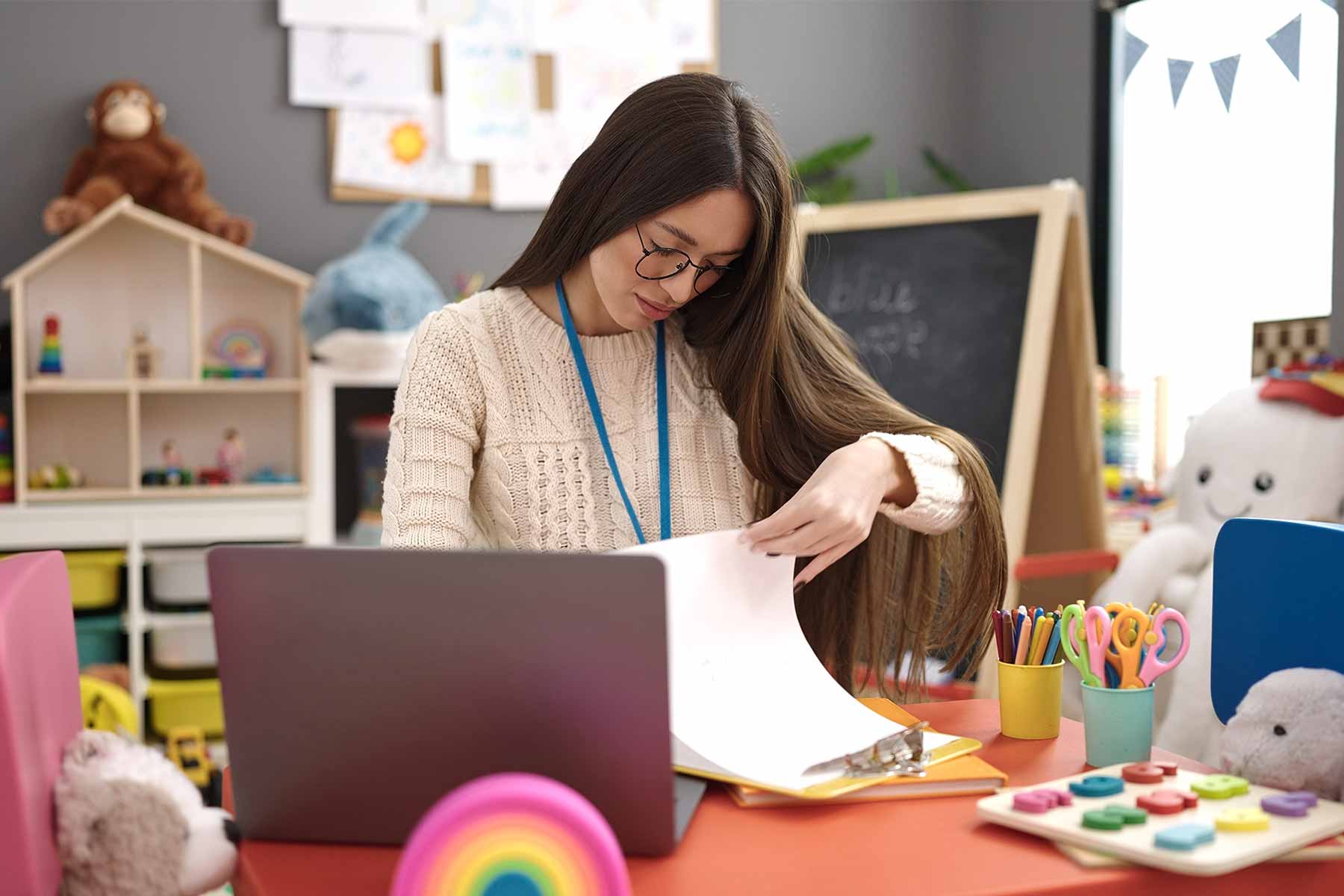 A daycare teacher reviewing her curriculum guide in a classroom