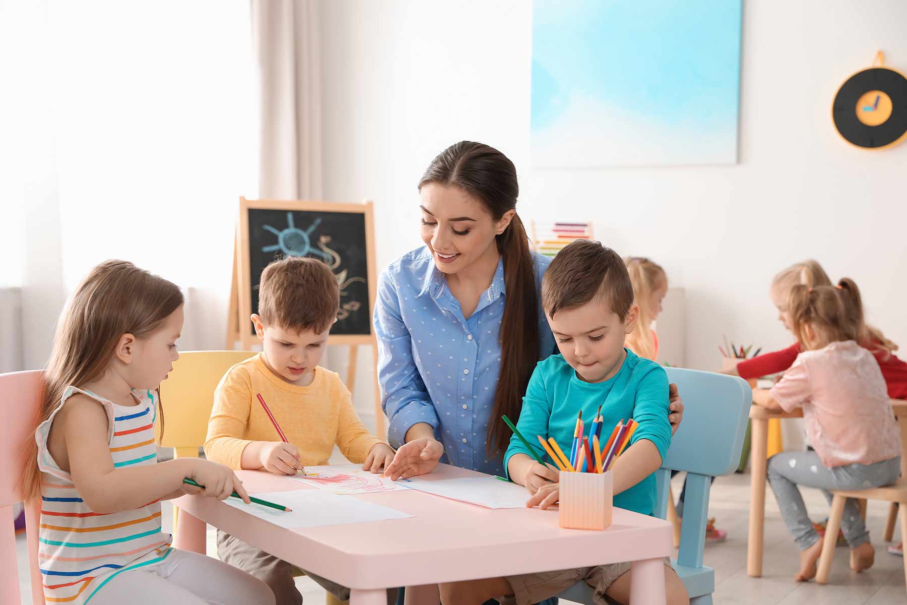 Daycare teacher helping kids with a coloring activity Daycare teacher helping kids with a coloring activity