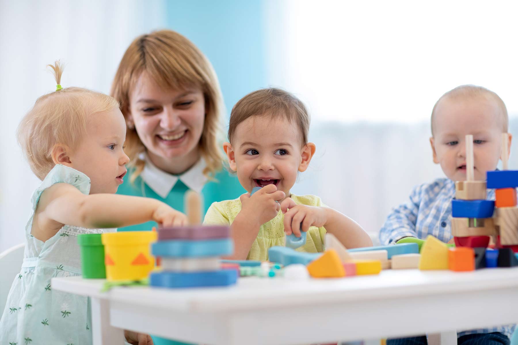 Children playing with their daycare teacher in a playroom