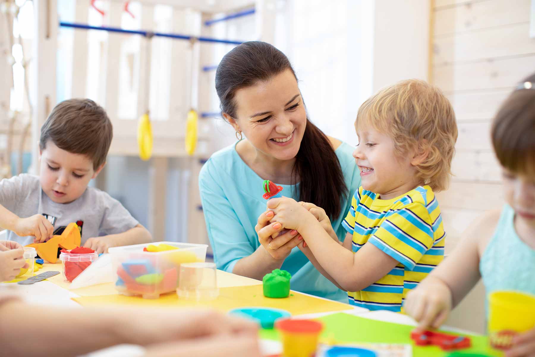 Daycare teacher playing with children with playdough