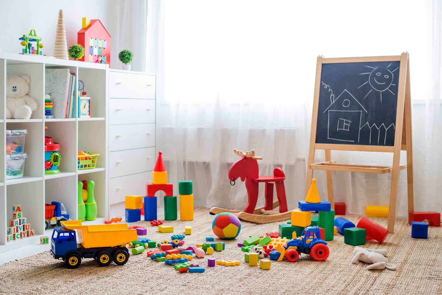 Colorful toys on shelves and a rug, a rocking horse, and a chalkboard at a daycare or preschool Colorful toys on shelves and a rug, a rocking horse, and a chalkboard at a daycare or preschool