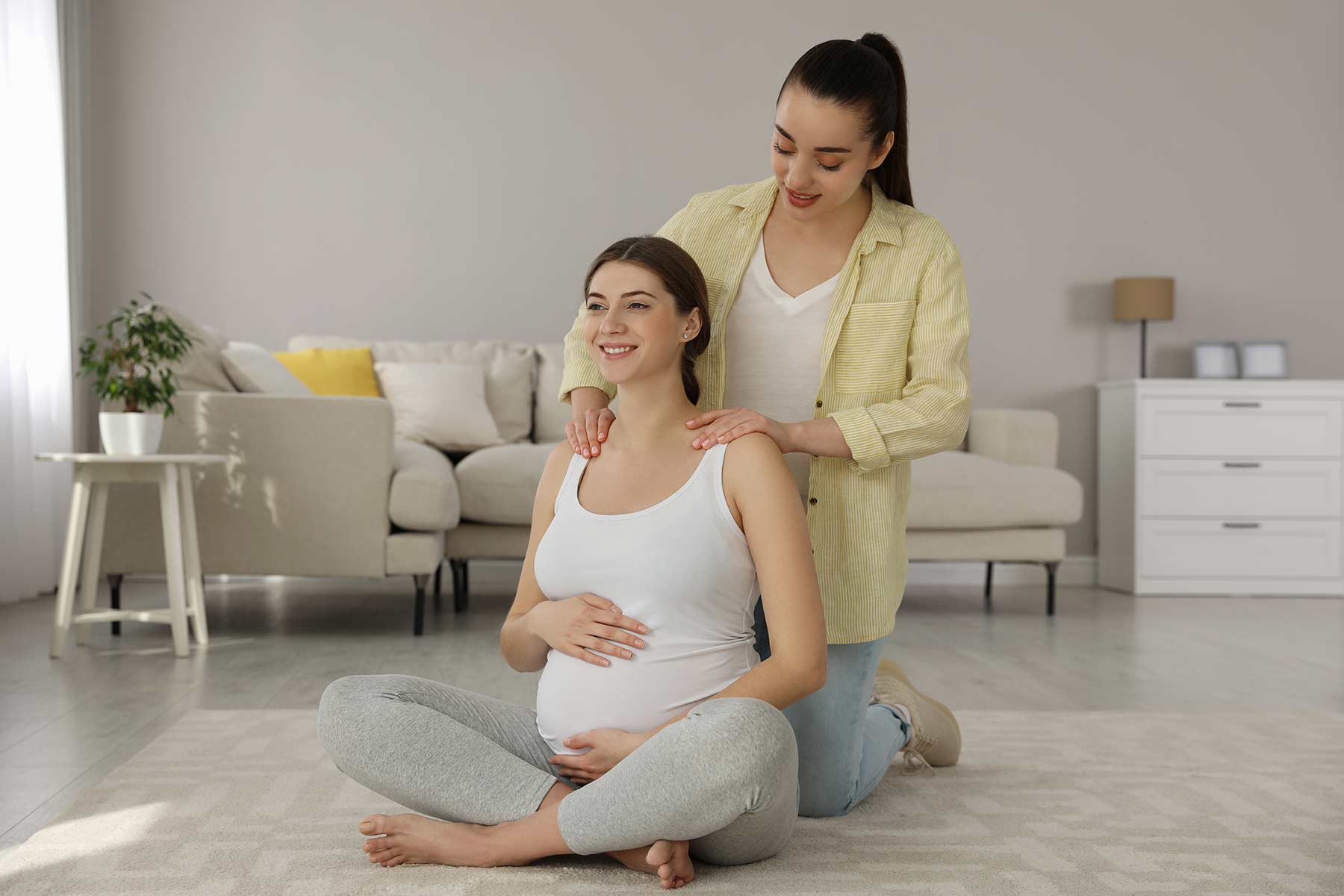 A doula massaging a pregnant woman at home to support relaxation and prepare for childbirth