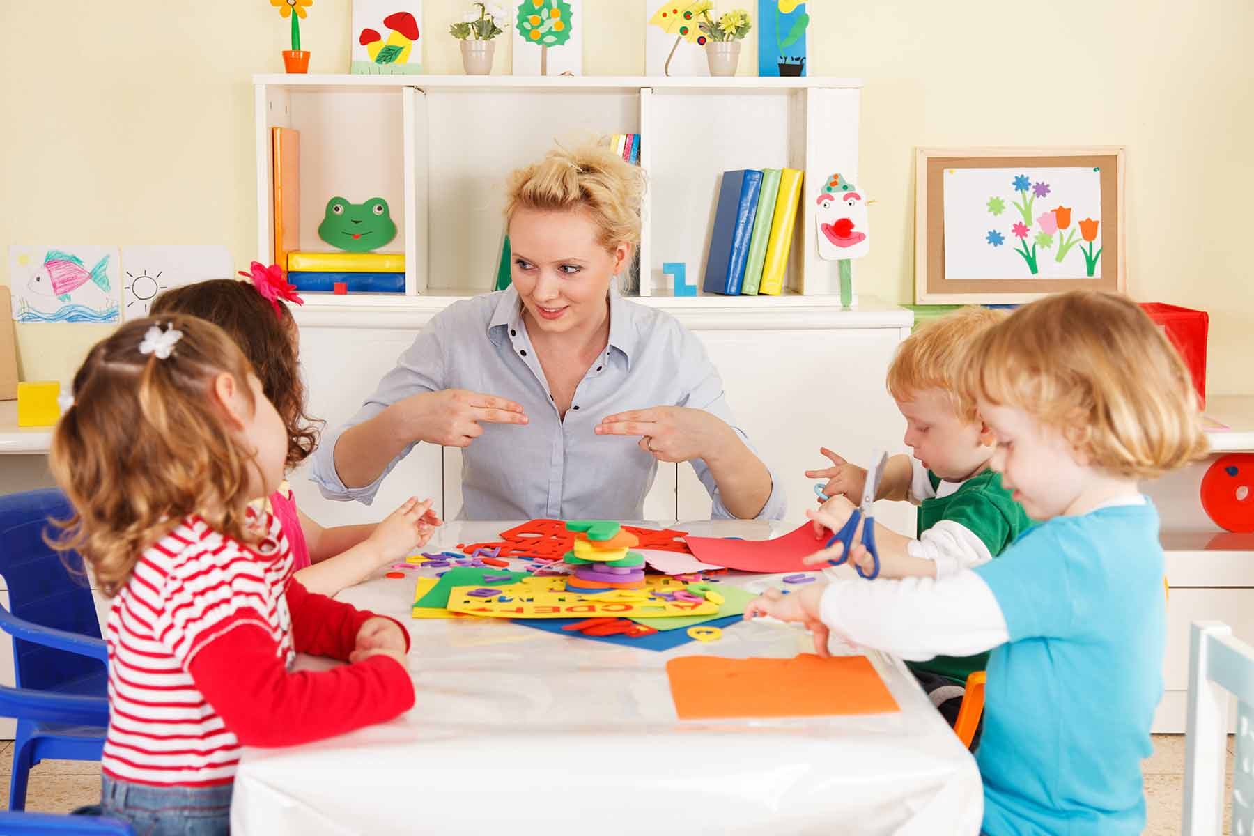 A daycare teacher guiding a group of children during a creative activity