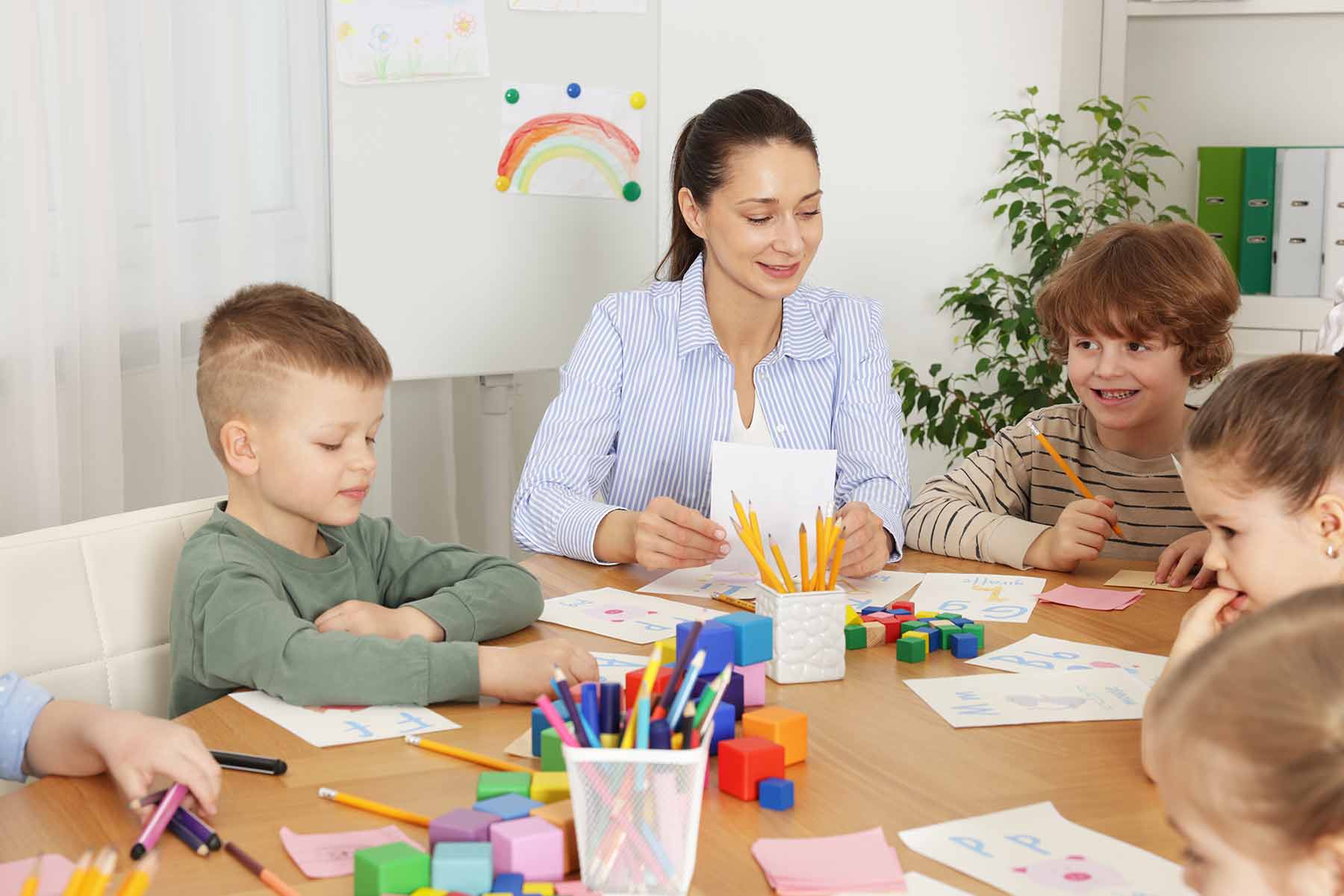 A daycare teacher looking after the children during a drawing and learning activity