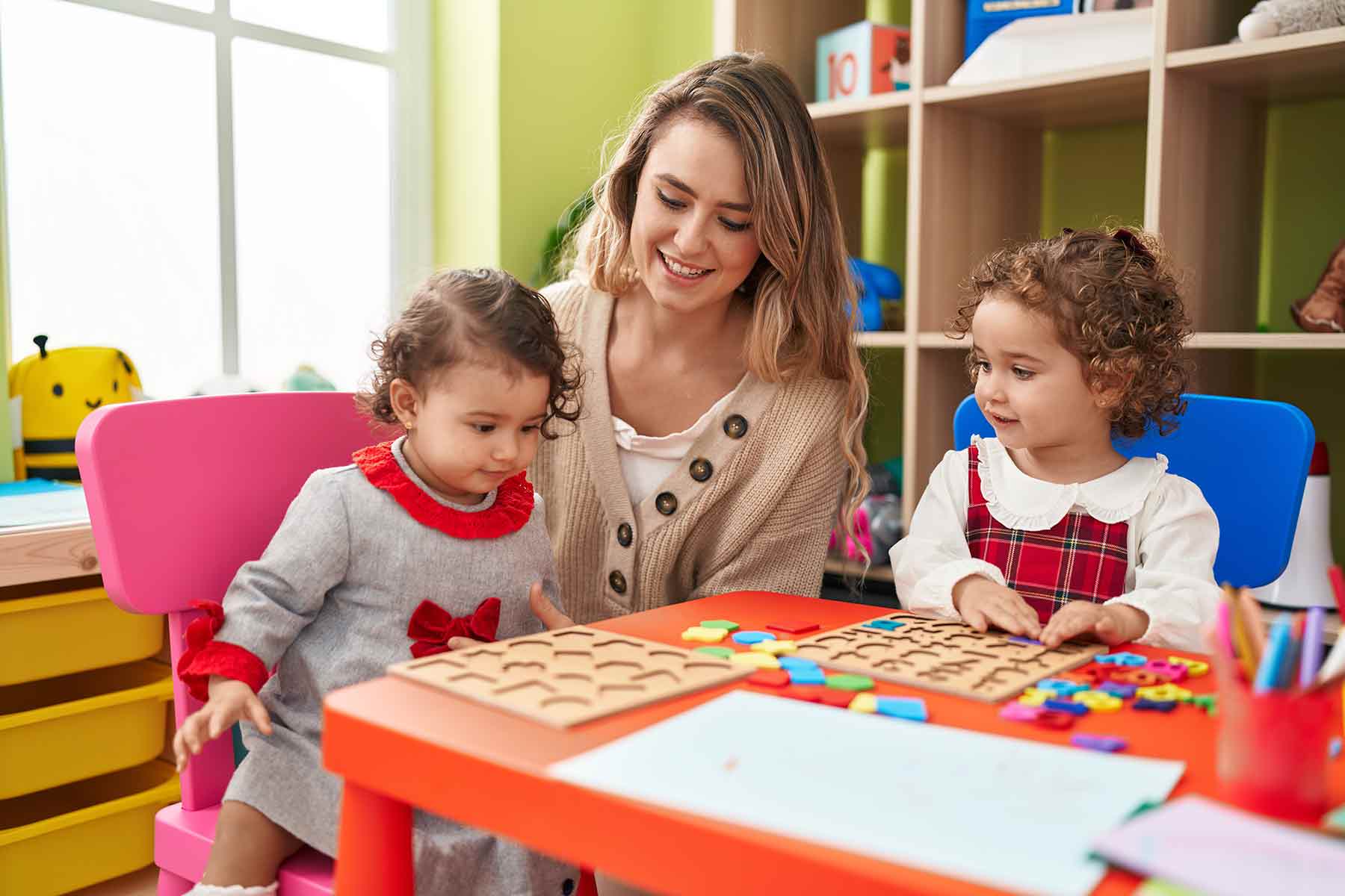Children playing math and shape puzzles with their teacher at a Montessori daycare center Children playing math and shape puzzles with their teacher at a Montessori daycare center