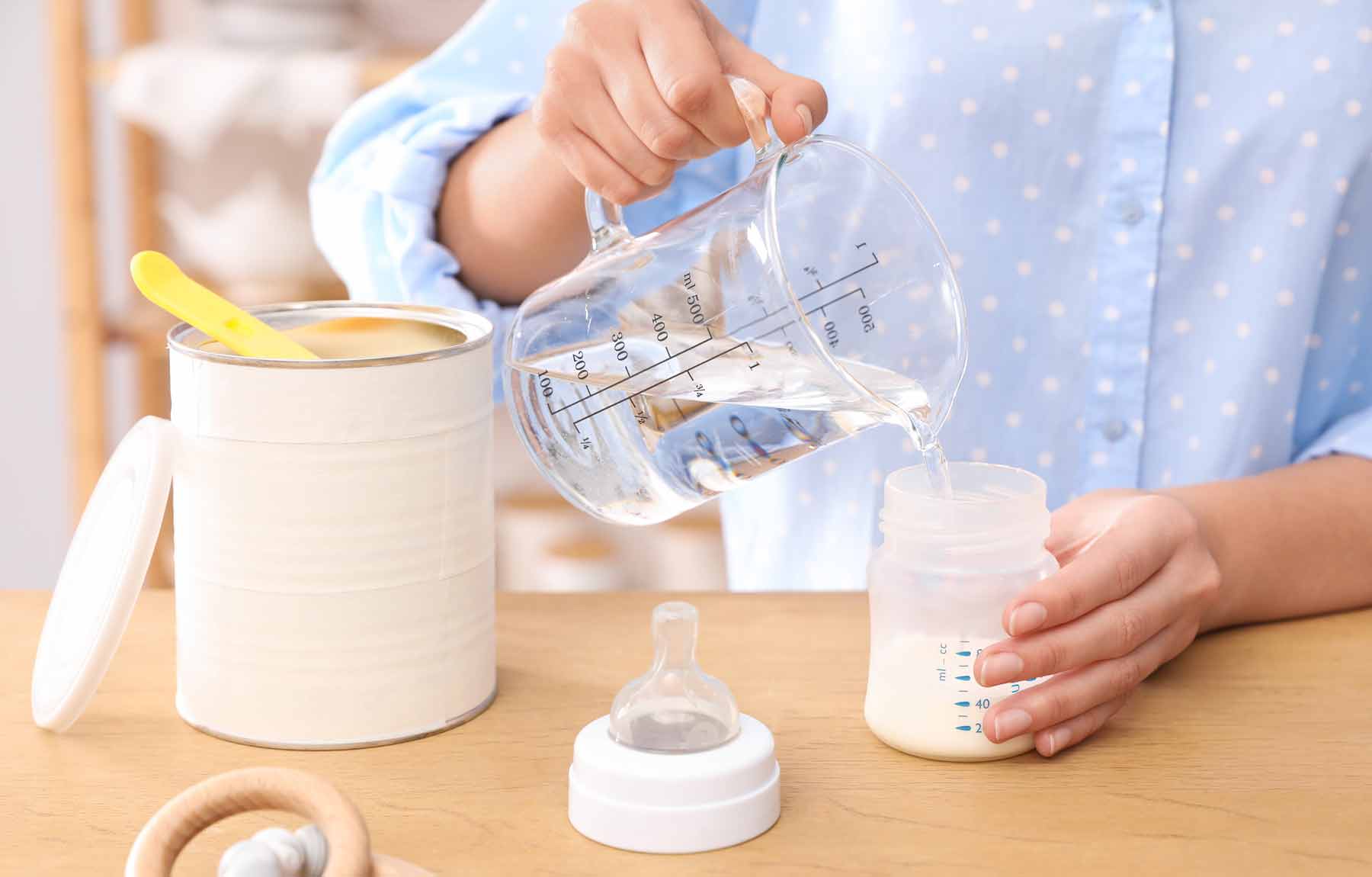 A mother preparing baby formula in a bottle.