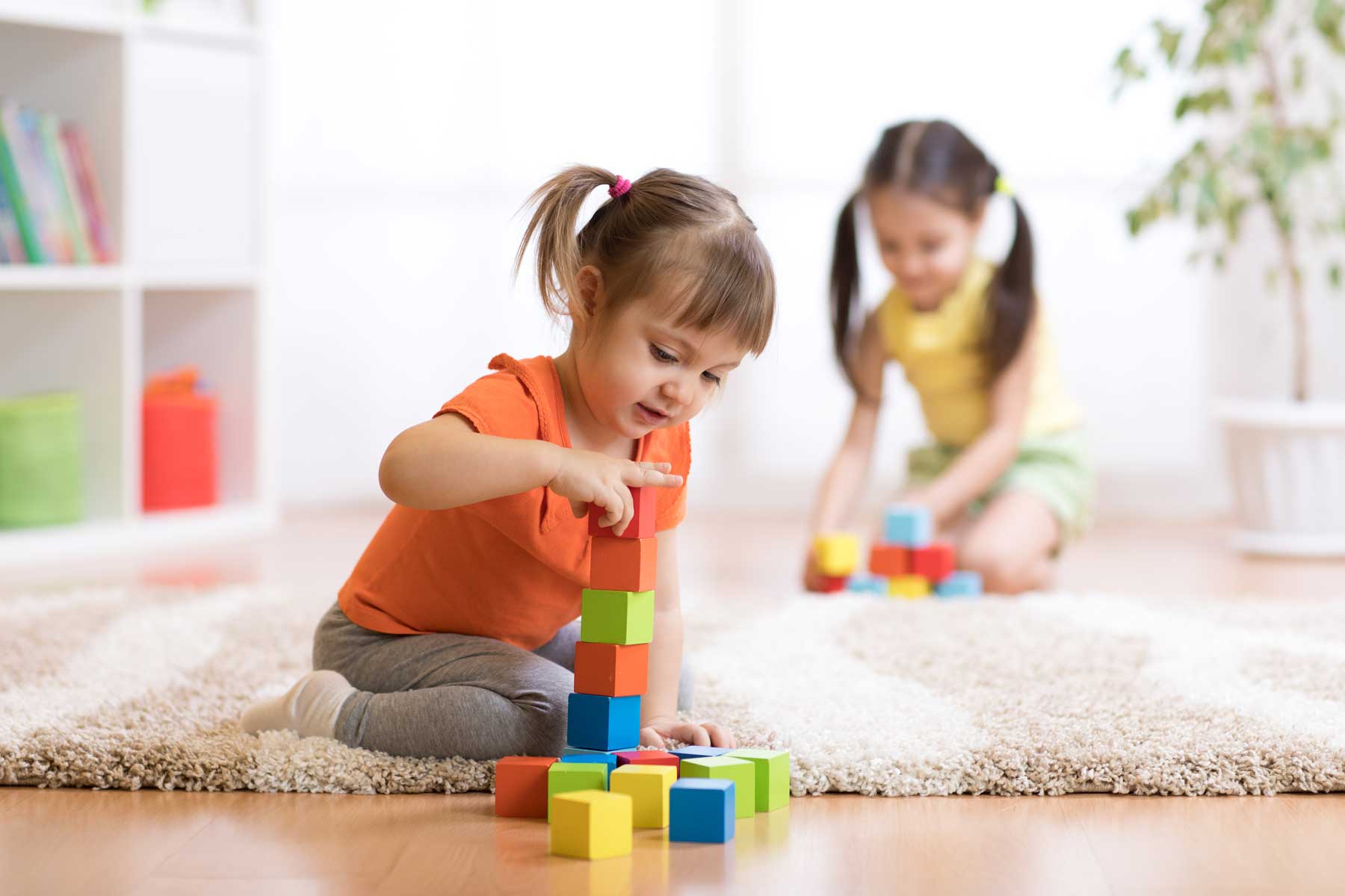 Two little girls playing with building blocks